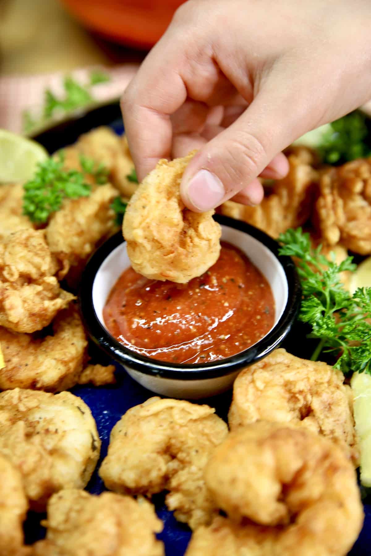Shrimp dipping into cocktail sauce.