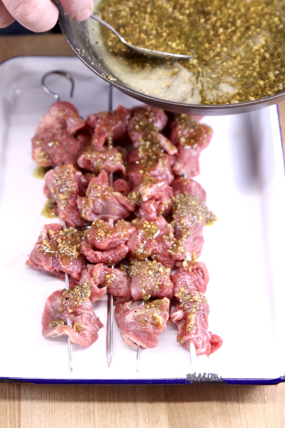 spooning garlic butter over steak skewers