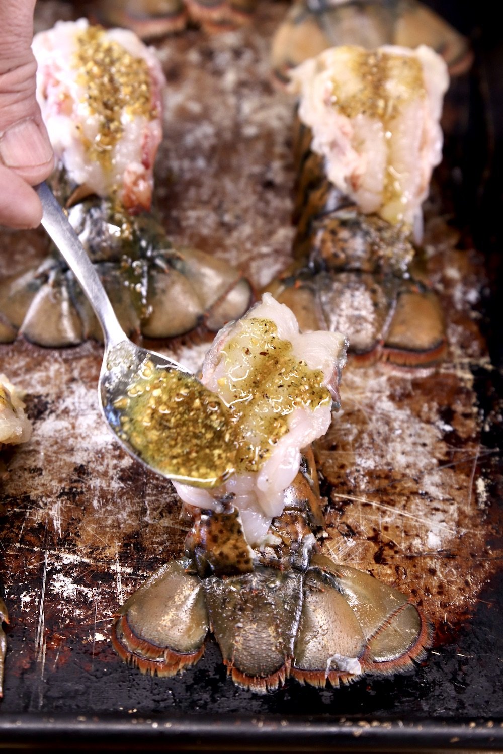 spooning garlic butter over butterflied lobster tails