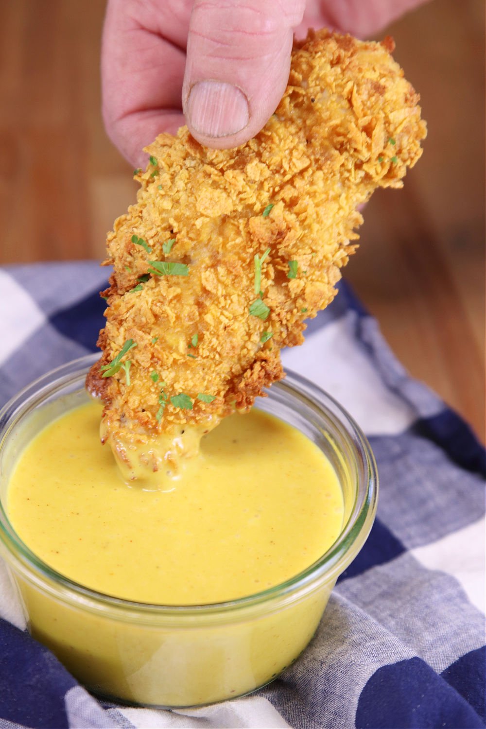 Cornflake chicken tender dipping in honey mustard sauce