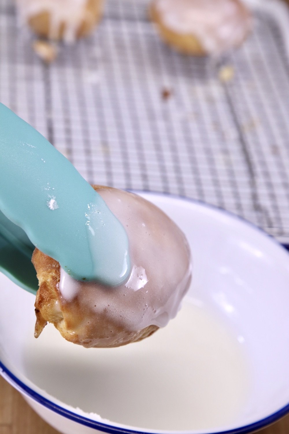 dipping peach cobbler bombs in powdered sugar icing