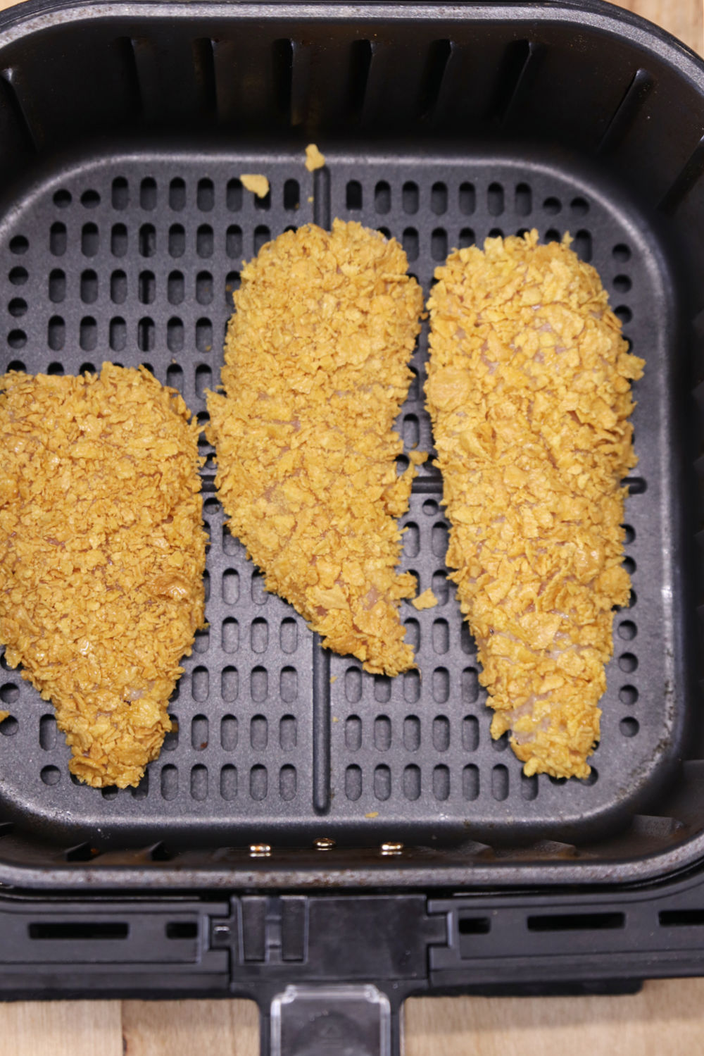 3 breaded chicken tenders in air fryer basket