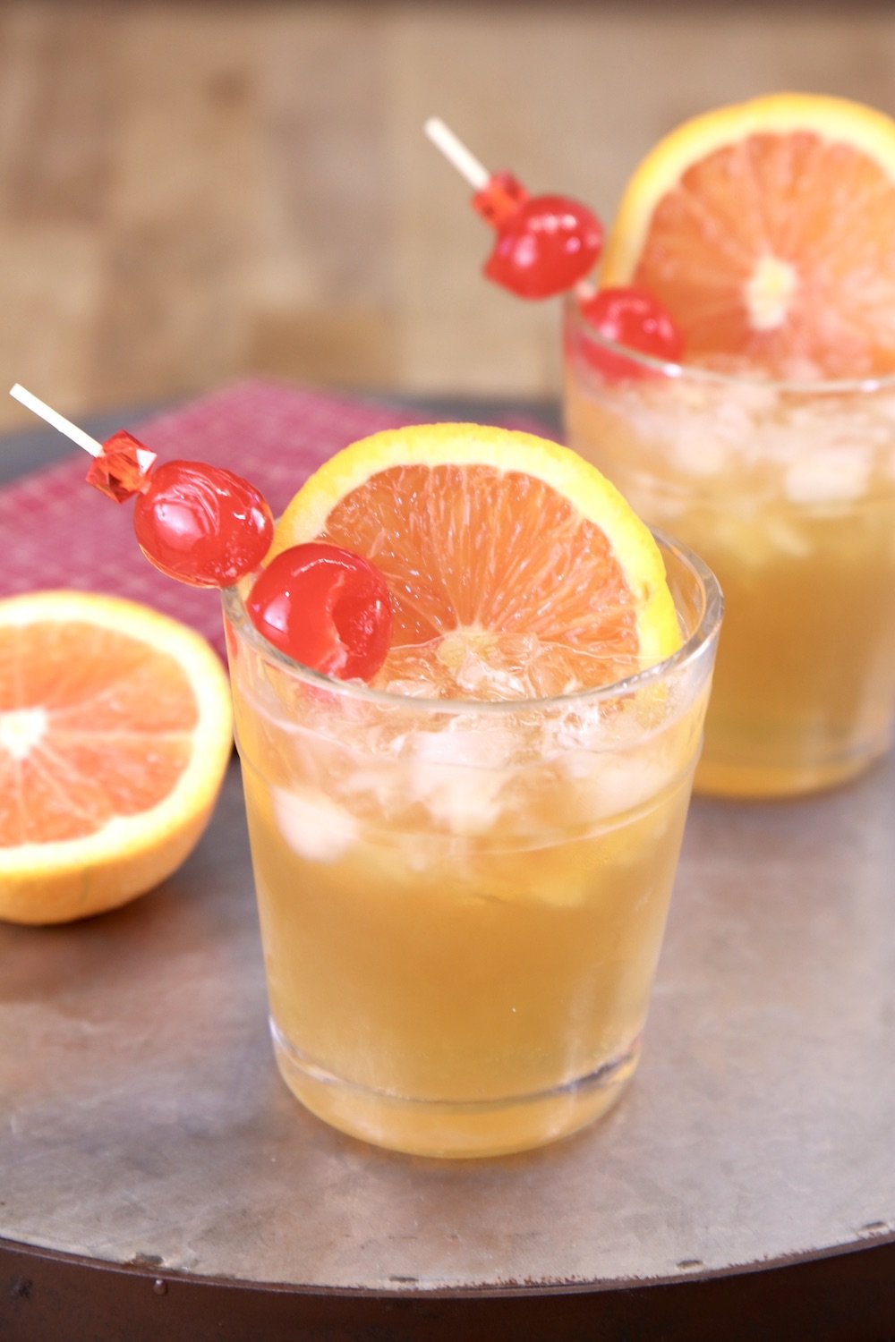 2 amaretto sour cocktails garnished ith oranges and cherries