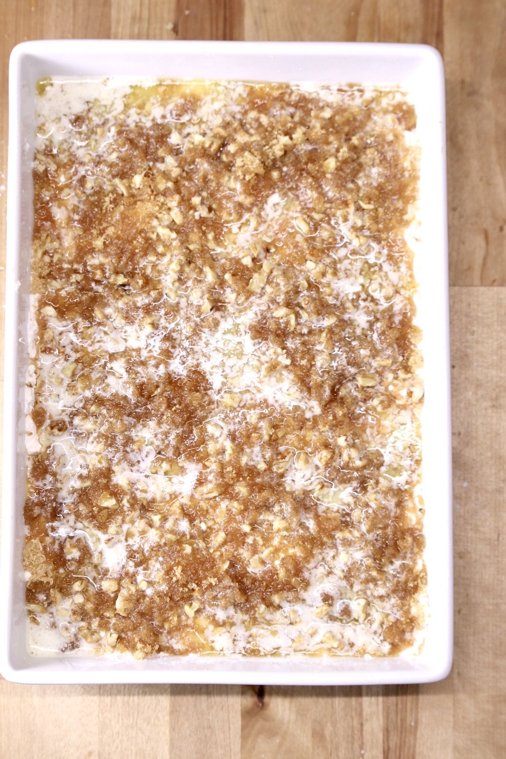 Dump cake topped with brown sugar, pecans and melted butter