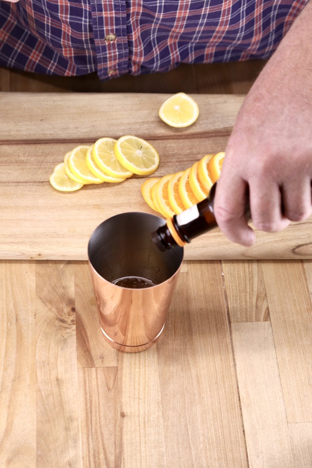 adding bitters to a cocktail shaker