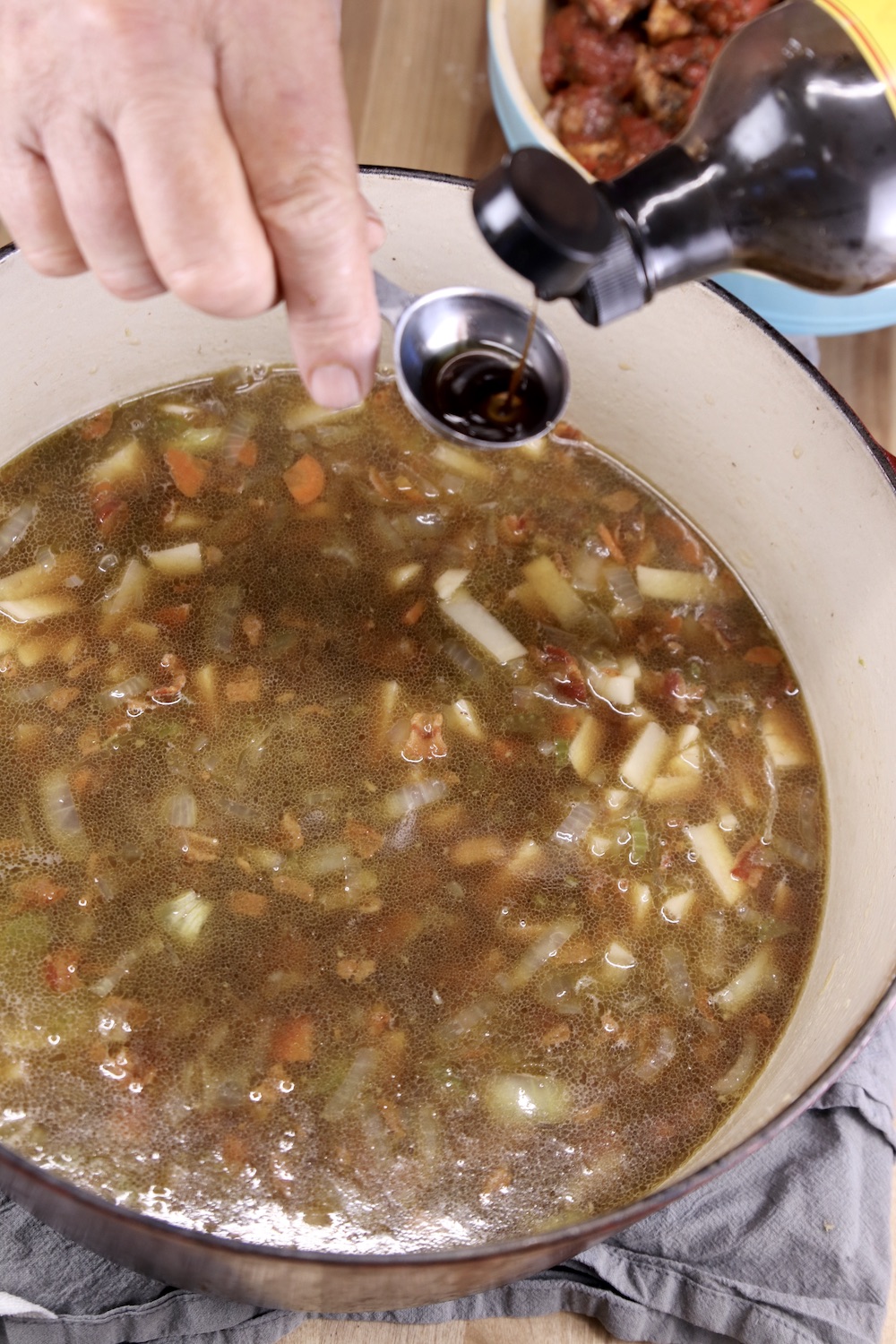 Adding Worcestershire sauce to pan of stew