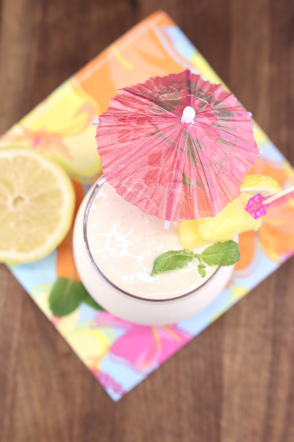 Overhead view of frozen lemonade cocktail with drink umbrella on a flowered napkin
