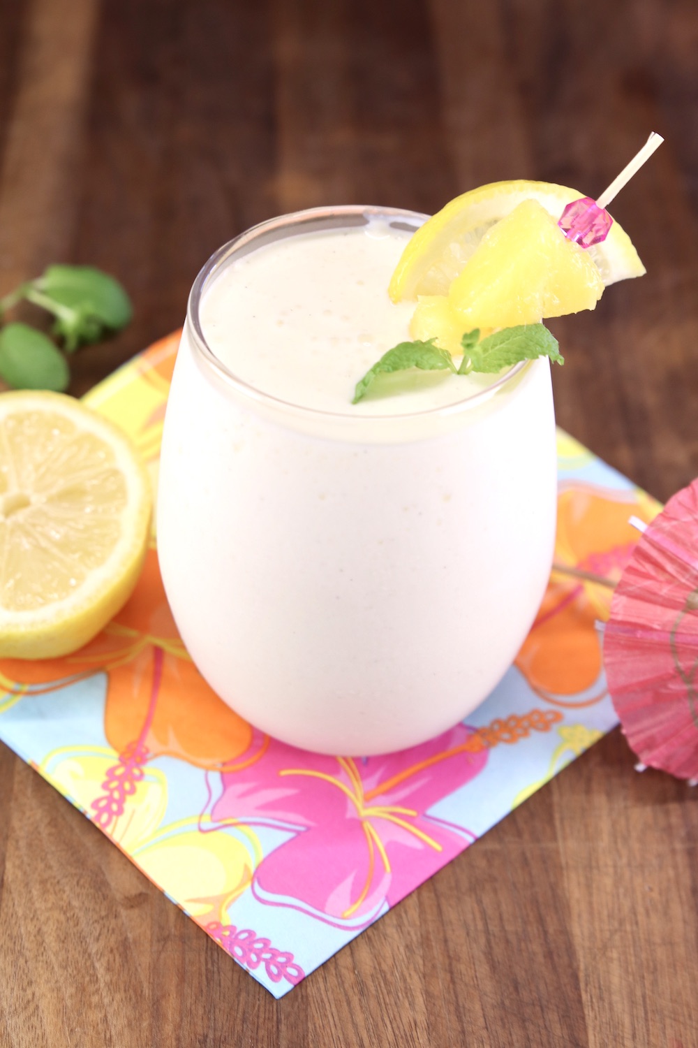 stemless wine glass with frozen lemonade cocktail - pineapple, lemon, mint and umbrella garnishes