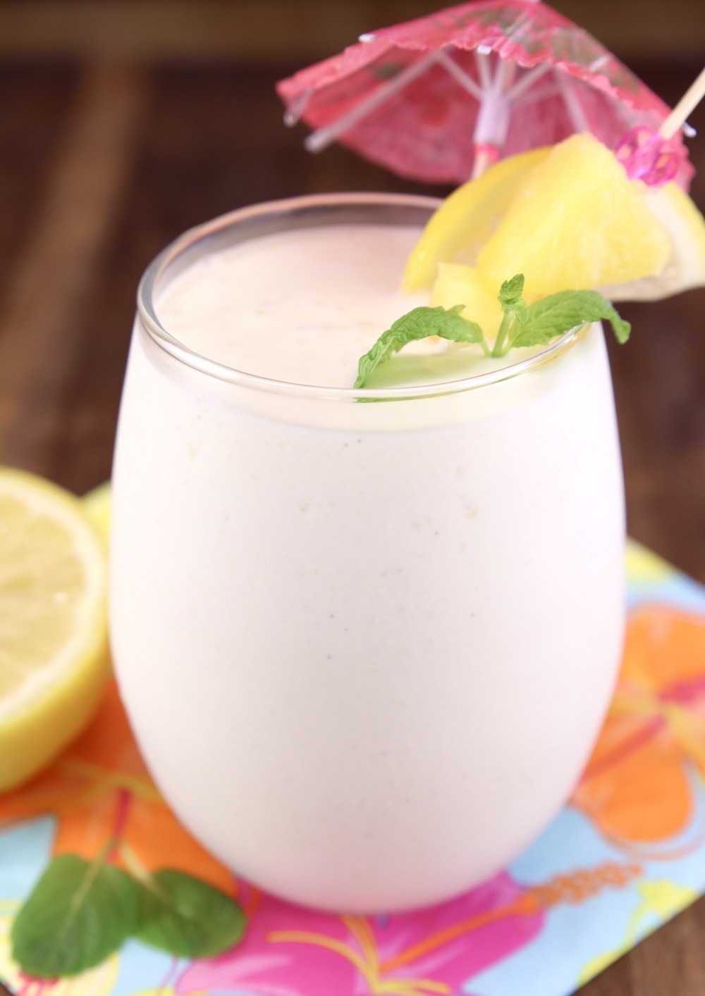 Frosted Lemonade Cocktail with drink umbrella, pineapple, lemon and mint garnish