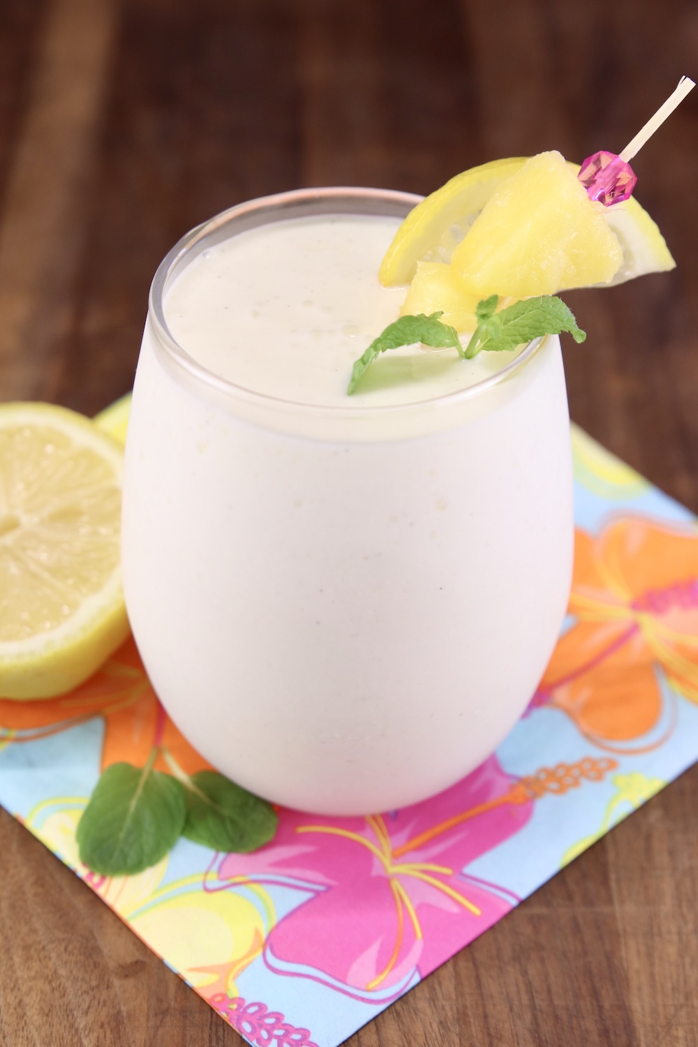 Frosted Vodka Pineapple Lemonade Cocktail in a stemless wine glass. Pineapple, lemon and mint garnish
