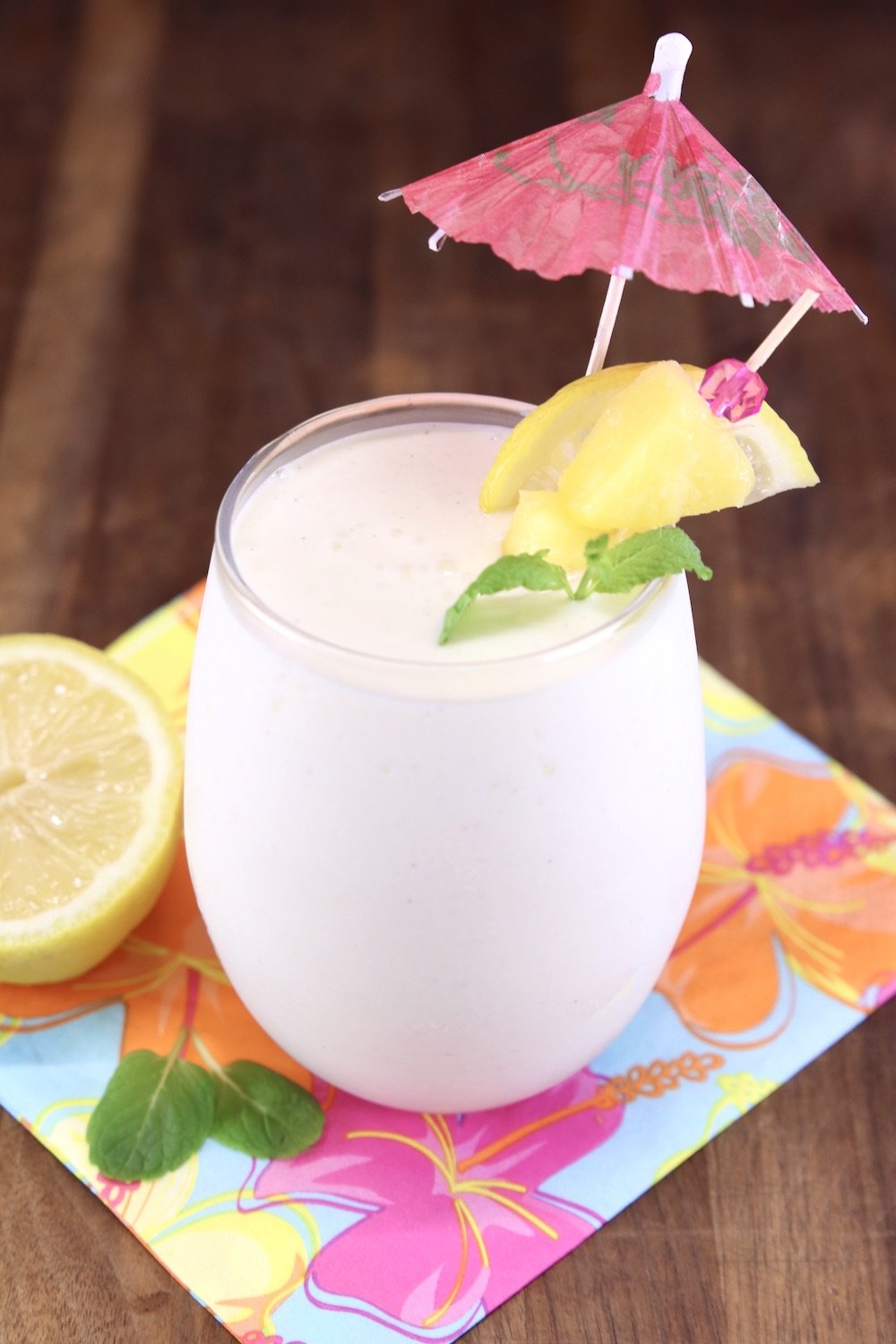 Frozen lemonade cocktail garnished with lemon, pineapple, mint and a pink umbrella