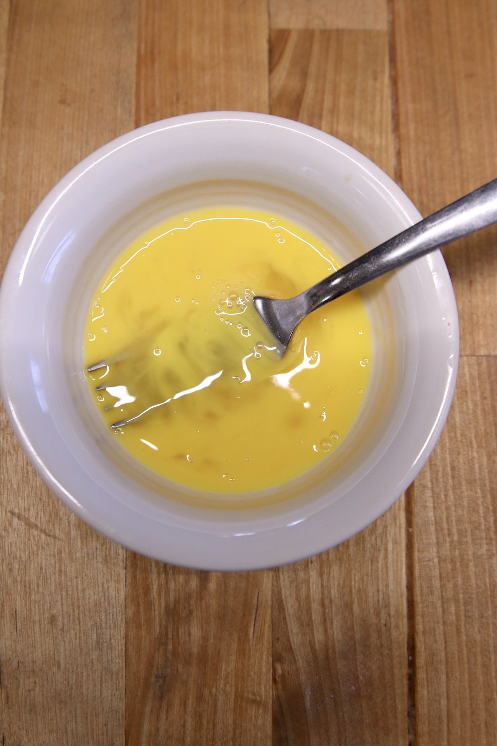 beaten egg in a bowl with a fork