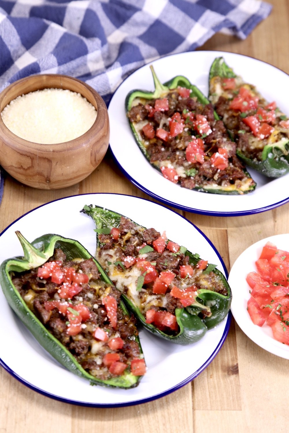 Plates of stuffed peppers topped with tomatoes