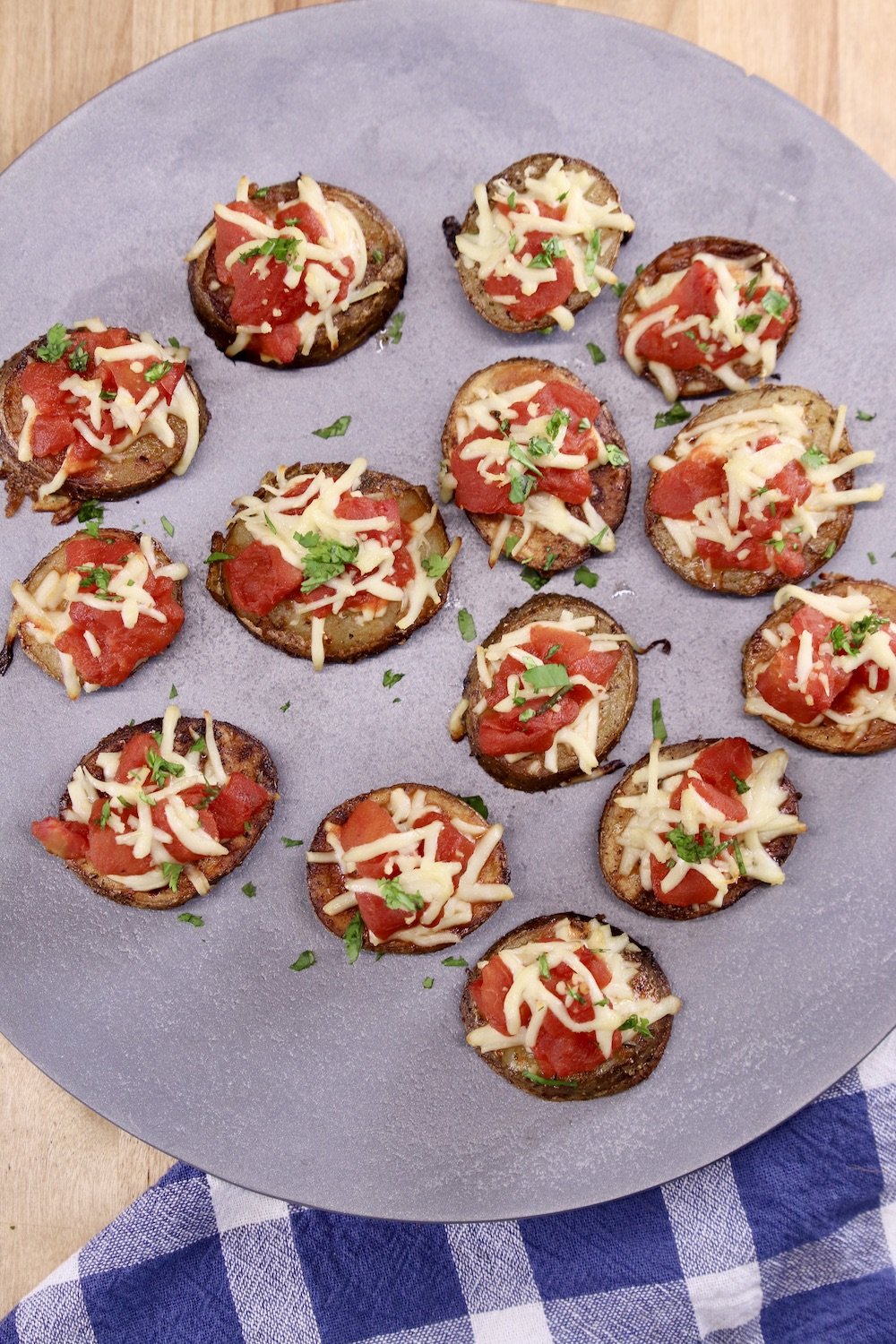 platter of potato slices topped with tomatoes and mozzarella