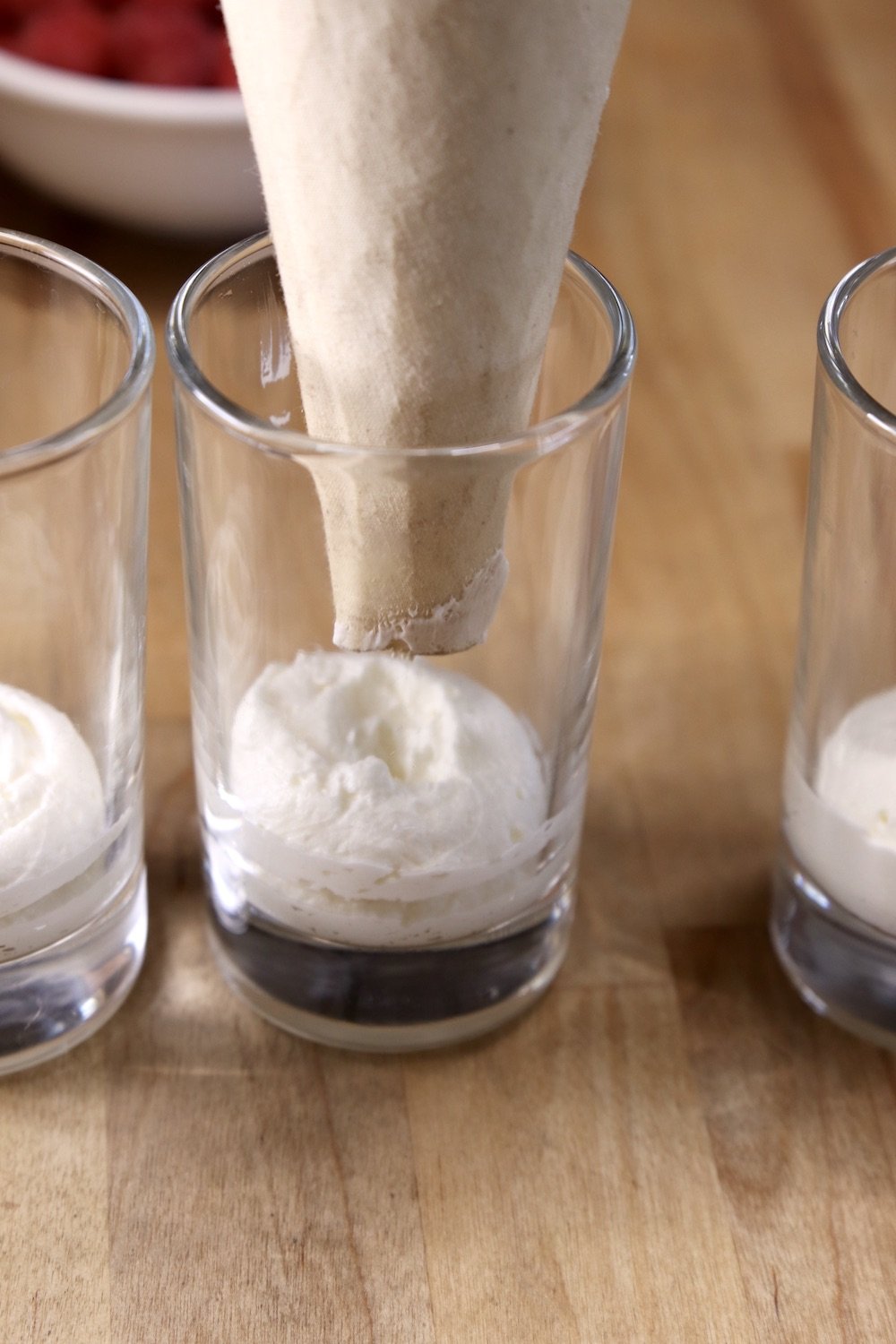 piping cheesecake filling into dessert glasses