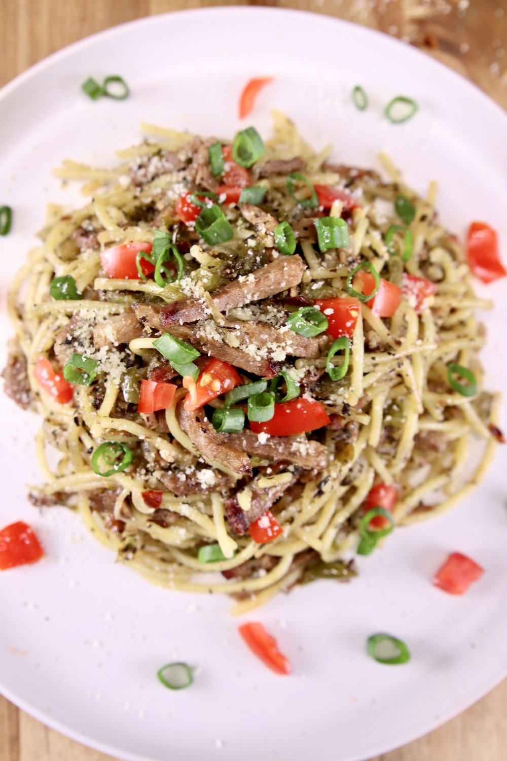 Brisket Spaghetti is a fabulous way to enjoy leftover smoked brisket from your weekend cookout. The smoky brisket is combined with pasta, peppers, onions and plenty of Italian spices for a quick and easy weeknight dinner. plate of brisket spaghetti with green onions and tomatoes