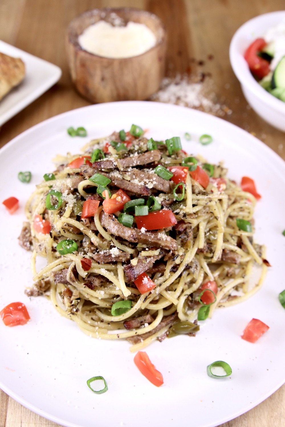 brisket spaghetti on a plate with chopped tomatoes and onions