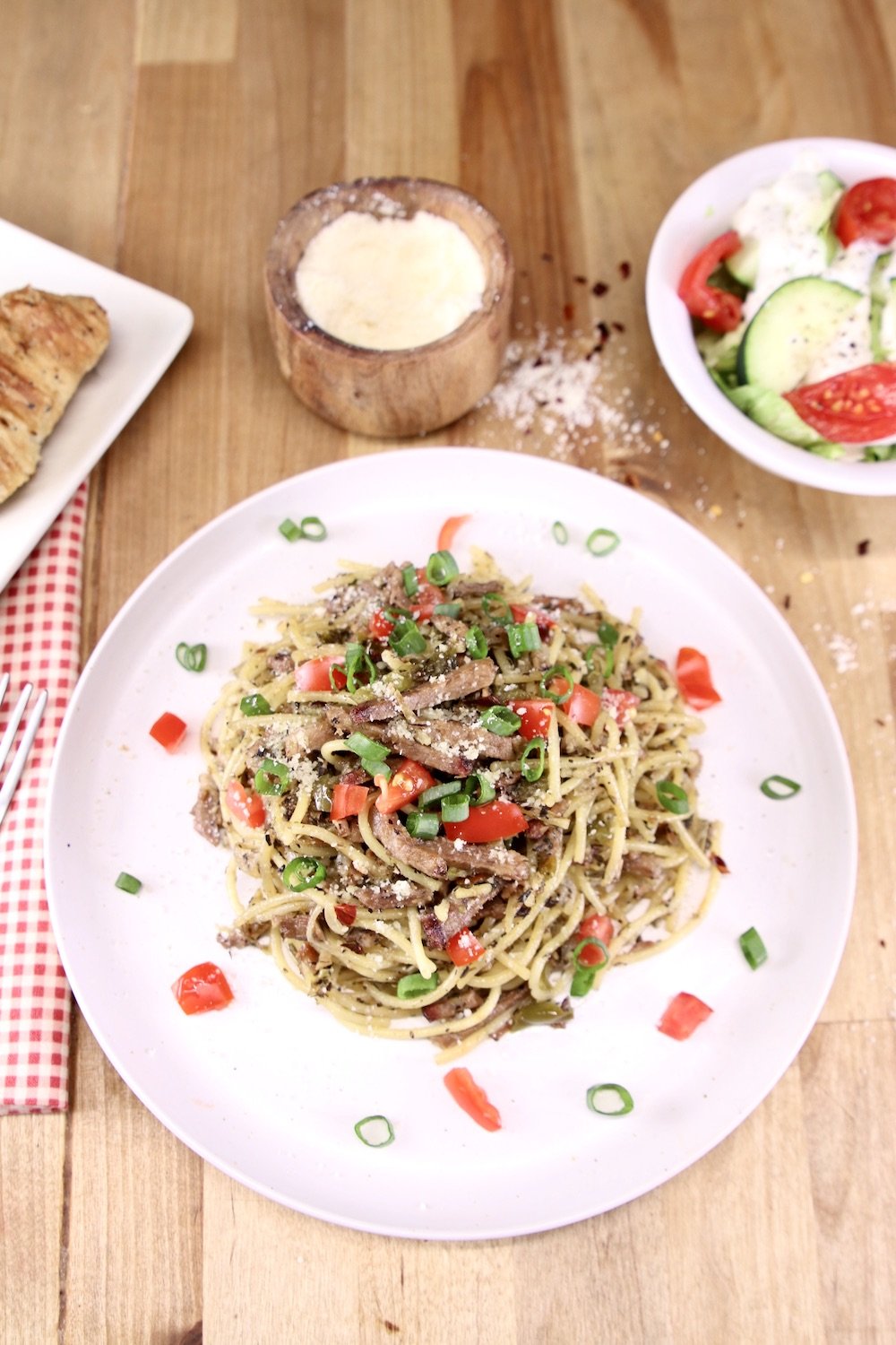 plate of brisket spaghetti with bowl of salad and small bowl of cheese