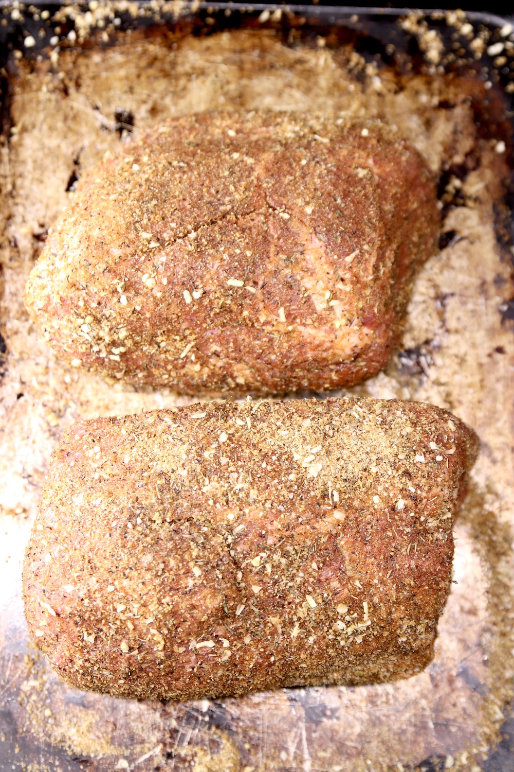 2 pork shoulder roasts with spice rub on a sheet pan
