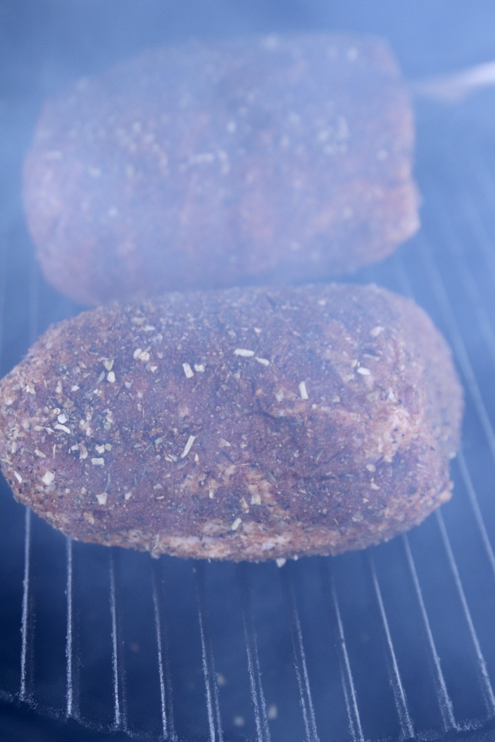 2 pork shoulder roasts on a grill with smoke