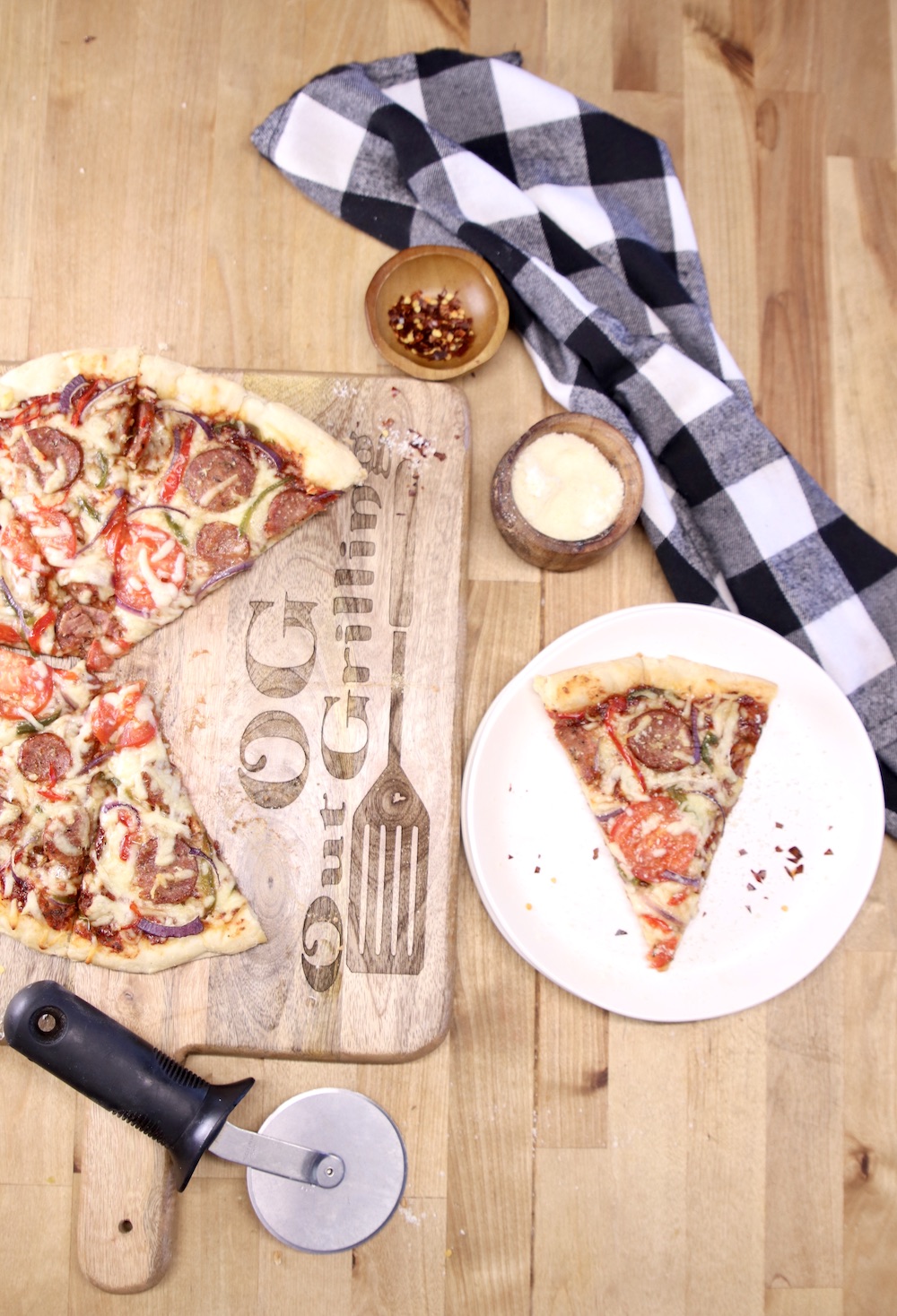 supreme pizza on a cutting board and one slice on a plate