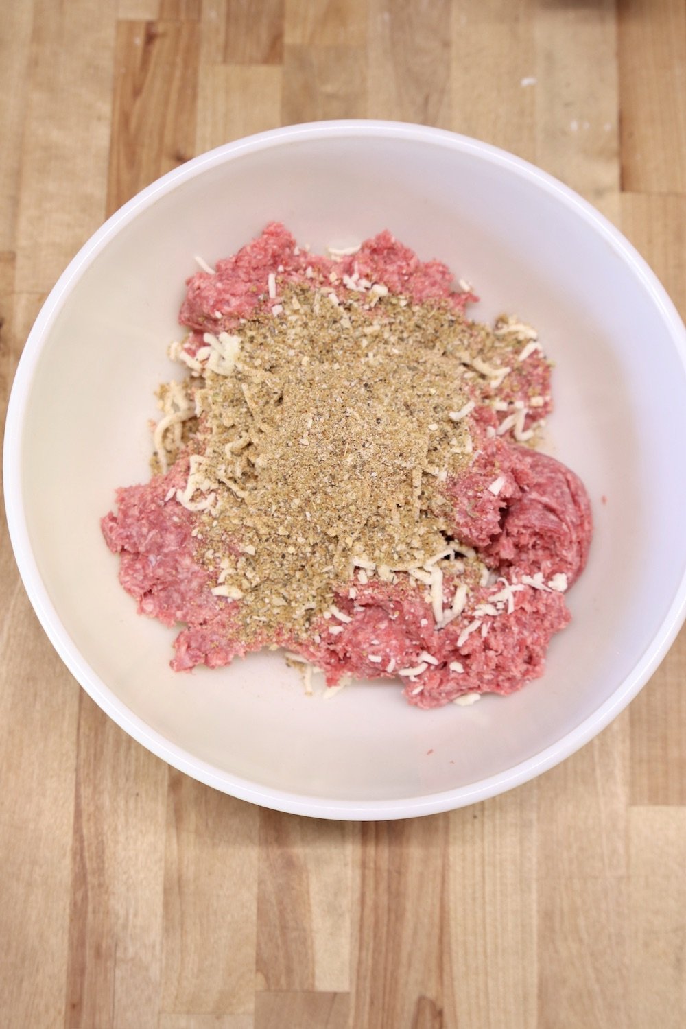 ground beef, shredded cheese and spices in a bowl