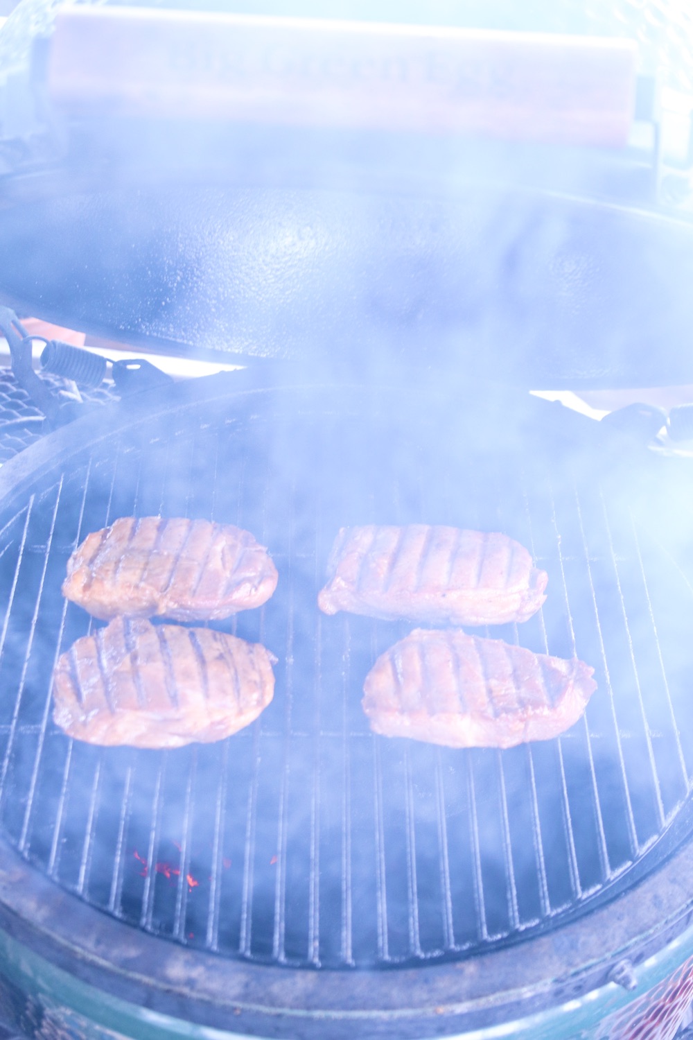 4 pork chops on a grill with smoke