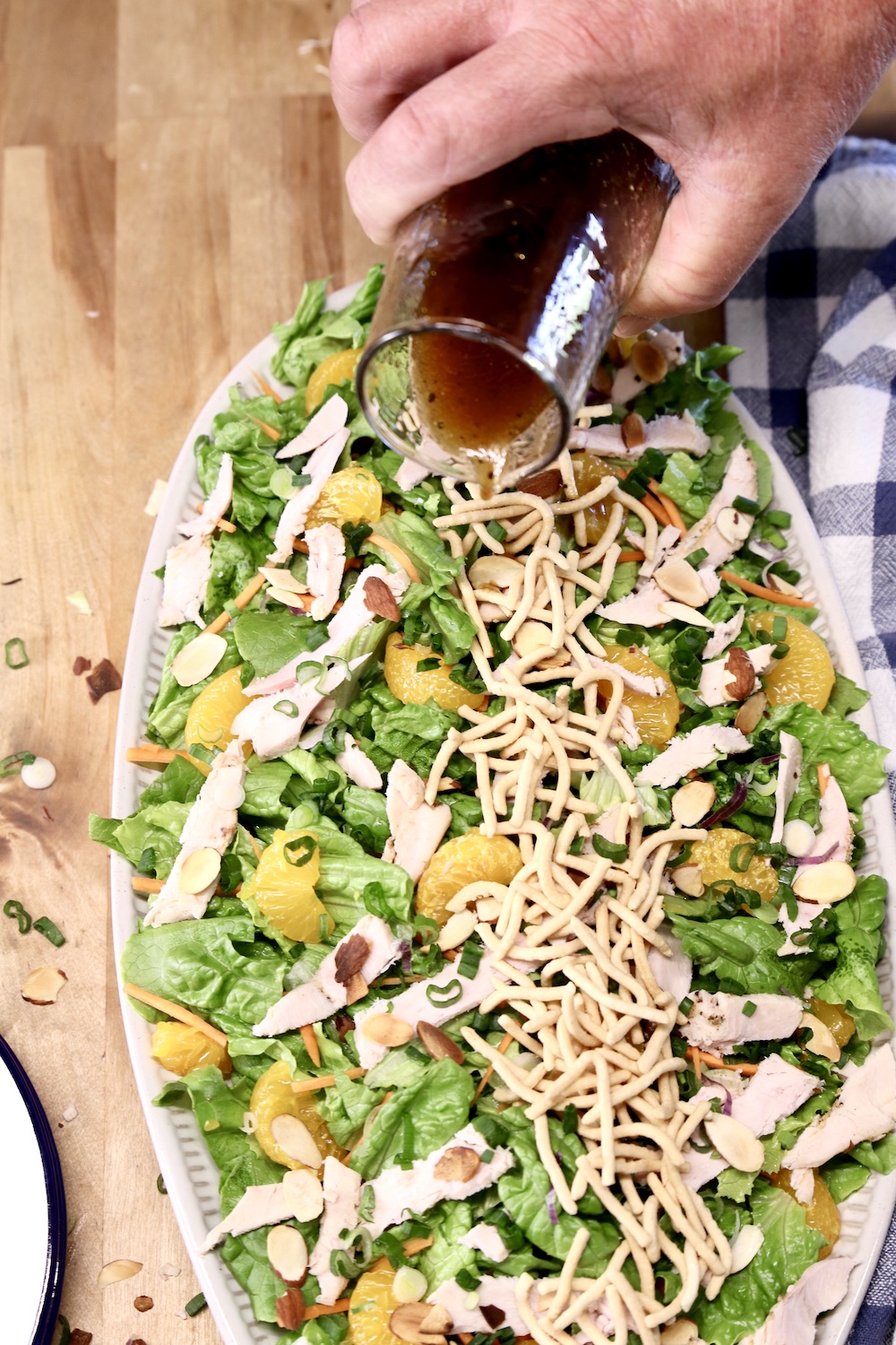 pouring dressing over platter of salad