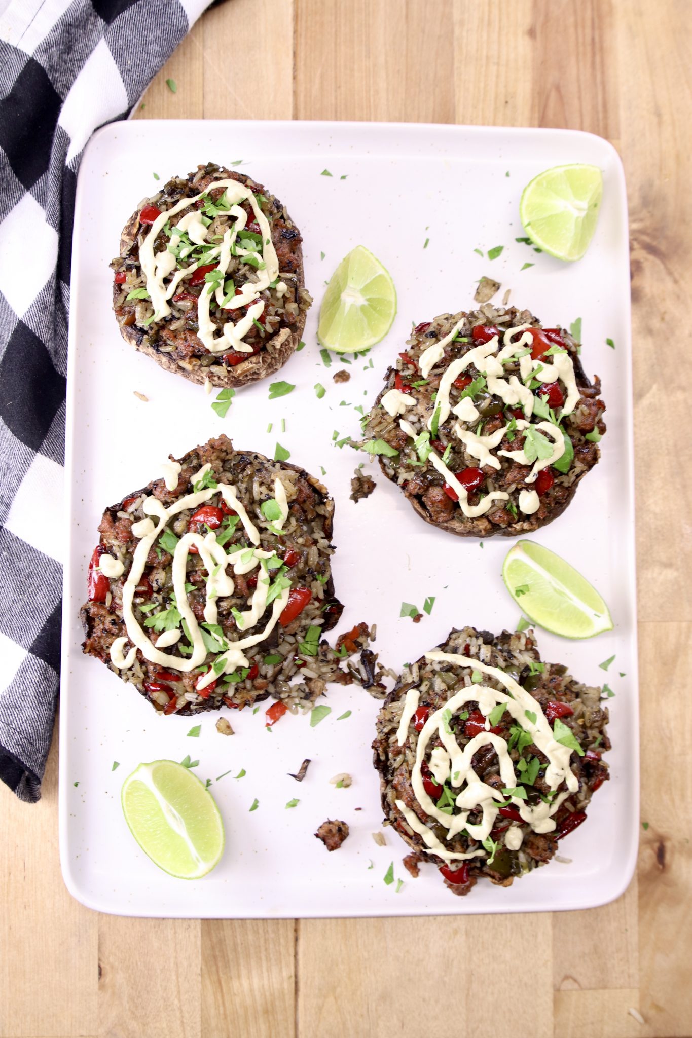 platter of 4 stuffed portobello mushrooms with sauce drizzled over the top