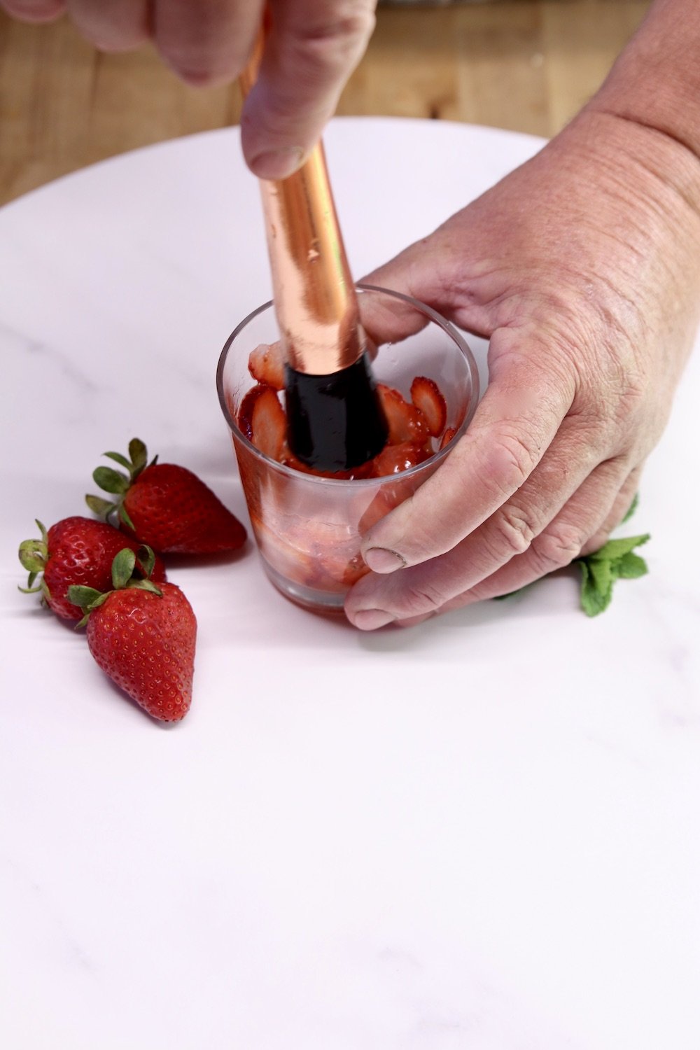 muddling strawberries in a glass