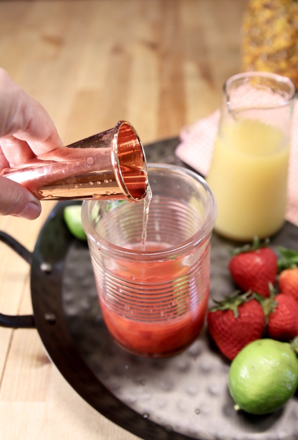adding rum to a glass for a cocktail