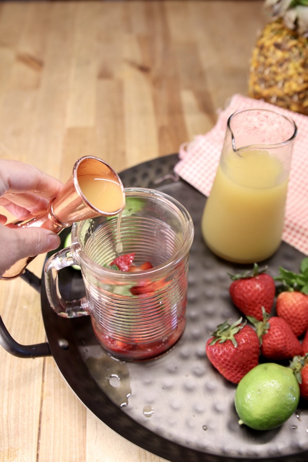 adding pineapple juice to a glass for a cocktail