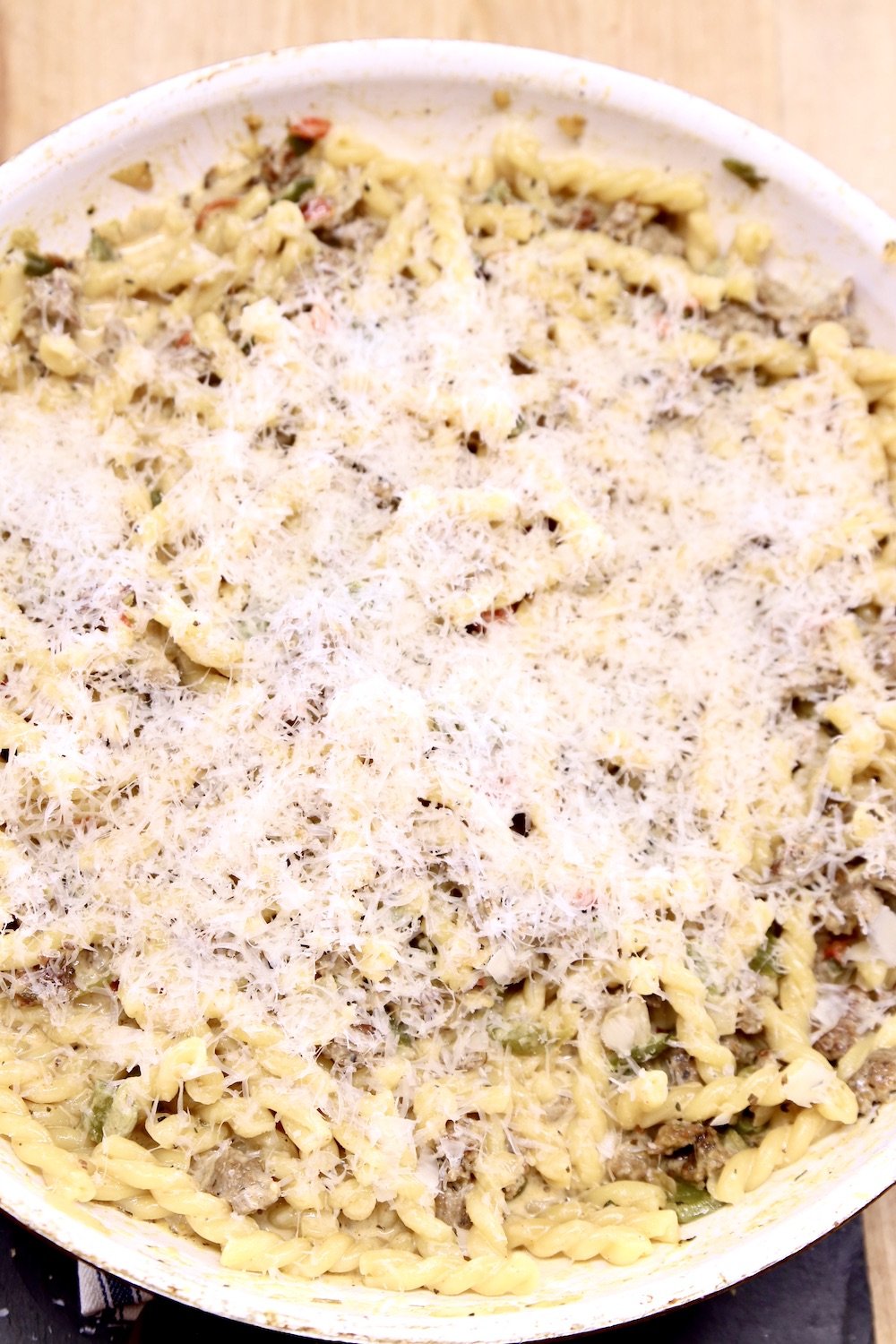 parmesan cheese over pasta in a skillet