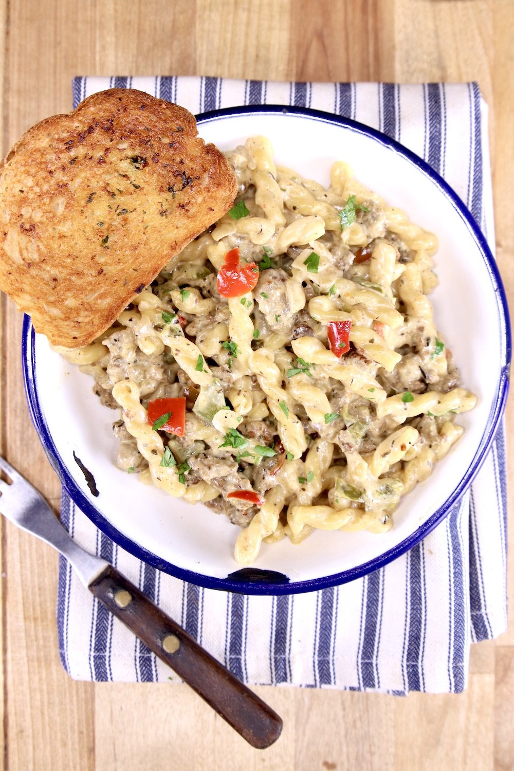bowl of pasta with garlic bread on a striped napkin