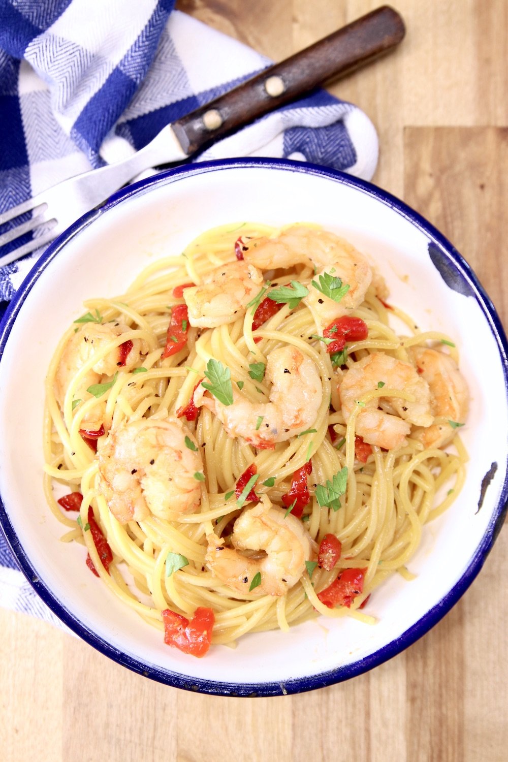 Honey Garlic Shrimp Spaghetti served in a bowl with a fork and blue check napkin
