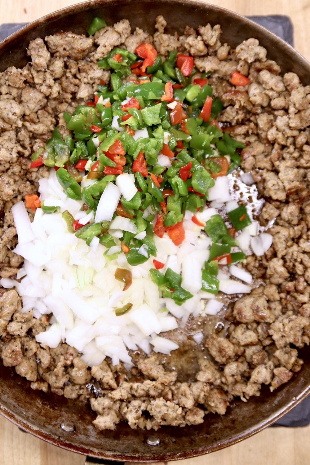 Browned sausage with diced peppers and onions in a skillet