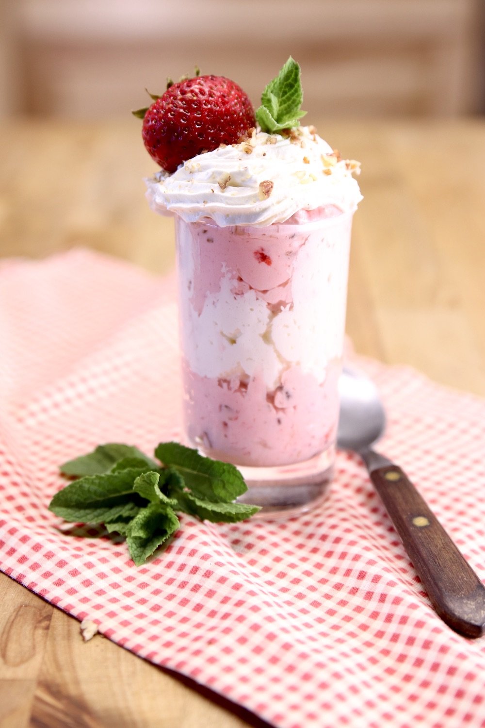 strawberry fluff dessert in a small glass with strawberry on top