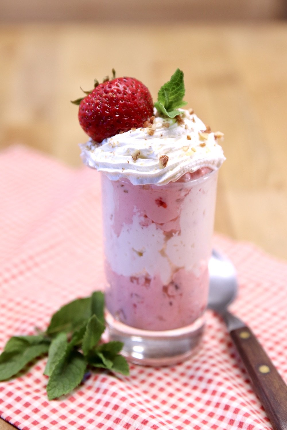 strawberry fluff layered in a dessert glass with cool whip. Strawberry on top