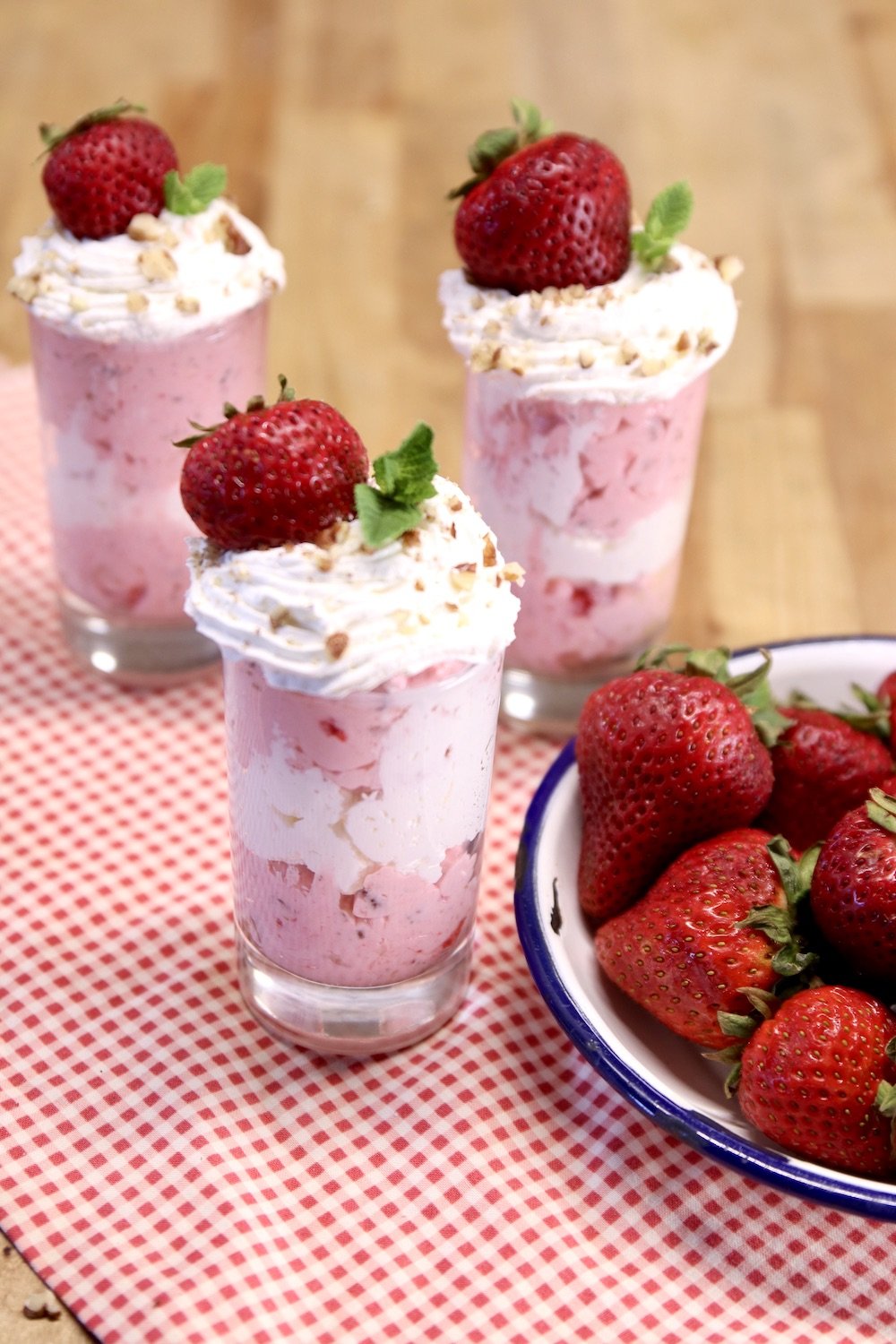3 dessert glasses with strawberry fluff dessert - topped with cool whip and a strawberry