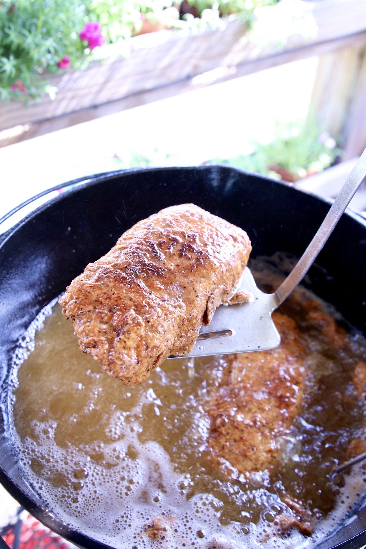 removing a fried pork chop from oil
