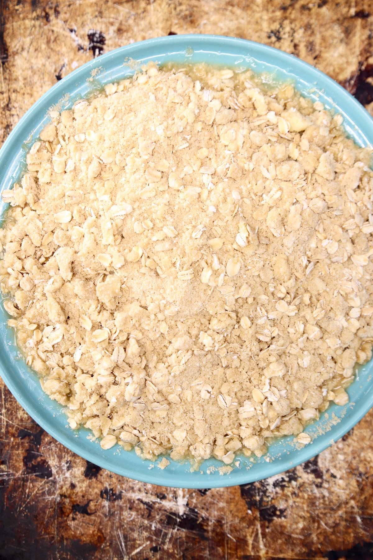 pineapple crisp in a pie plate on a baking sheet
