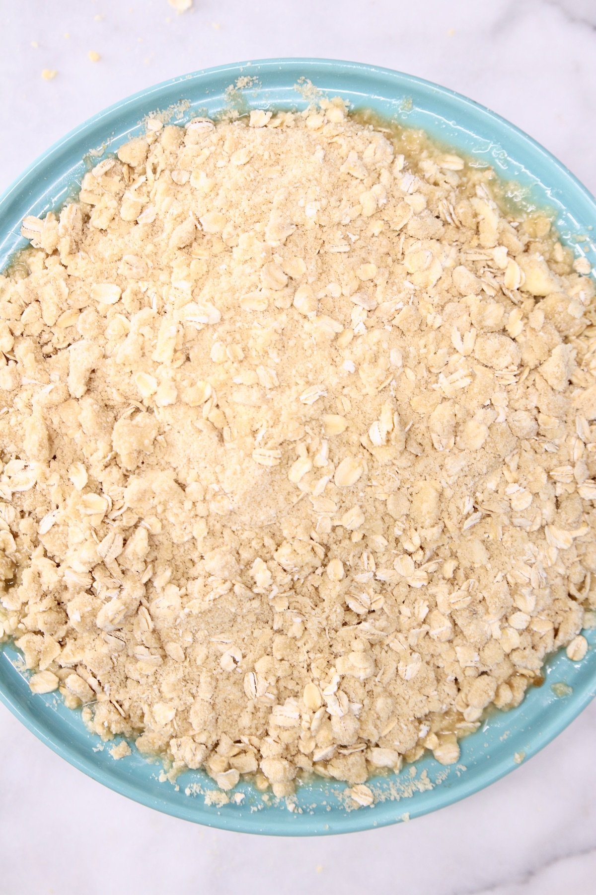 blue pie plate with pineapple crisp ready to bake
