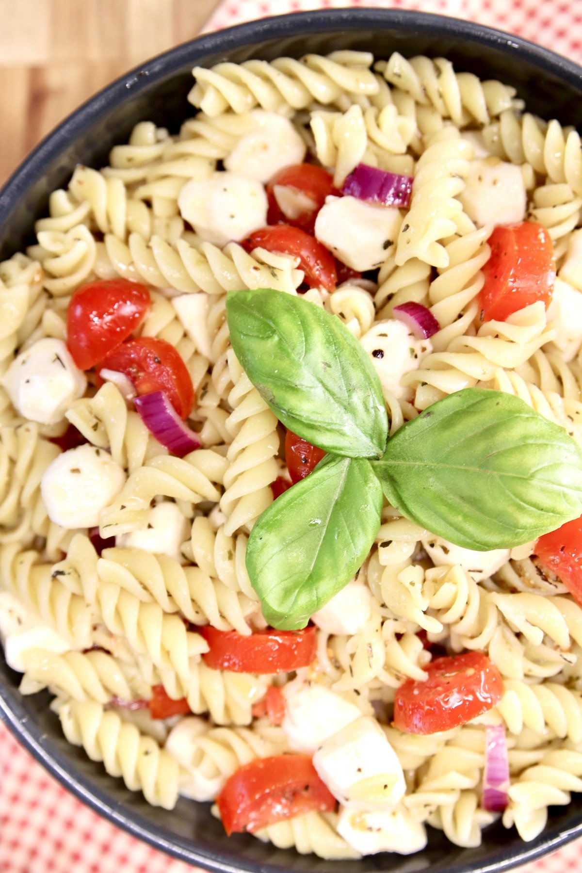 Tomato Mozzarella Pasta Salad with basil garnish