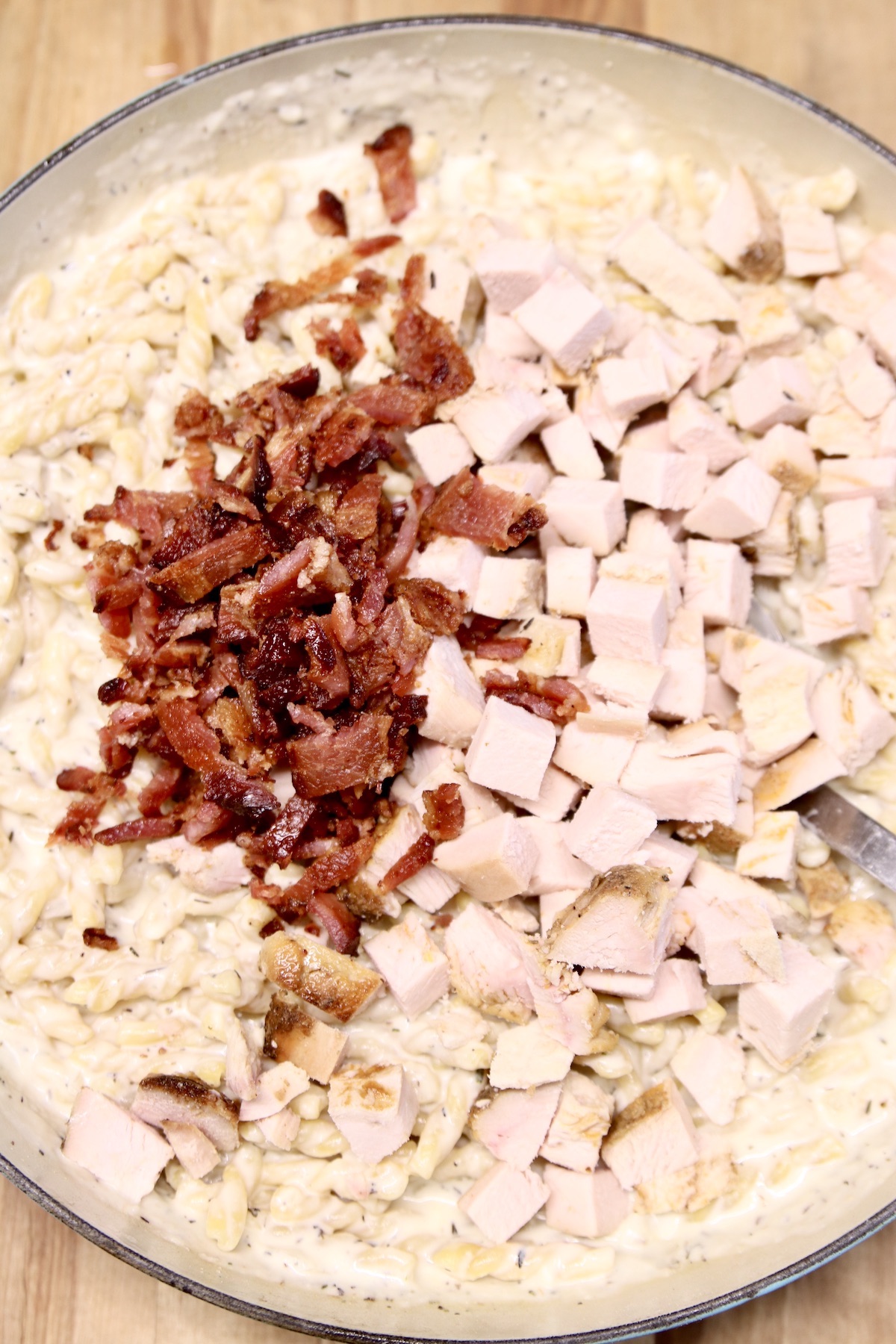 diced bacon and chicken in a pan with pasta