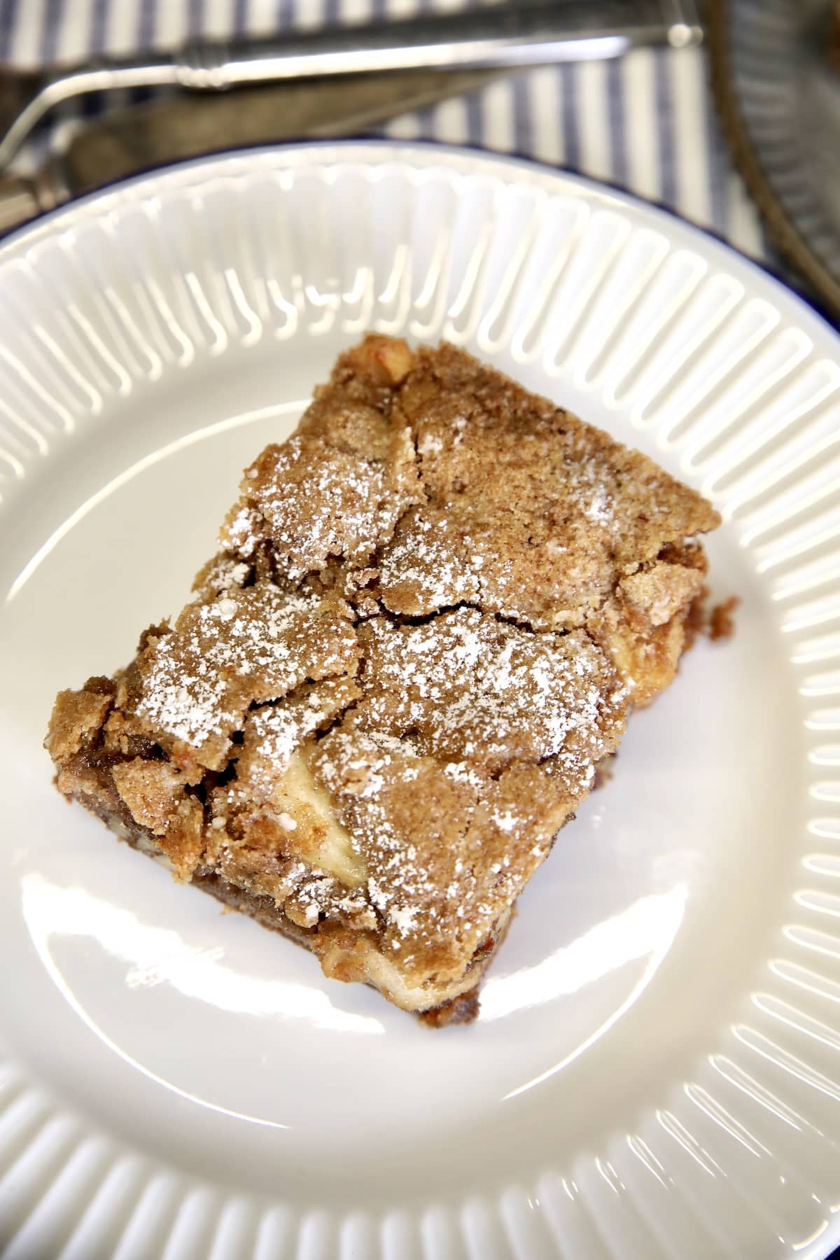 Best apple cake recipe with no mixer required. Apple cake slice with powdered sugar.