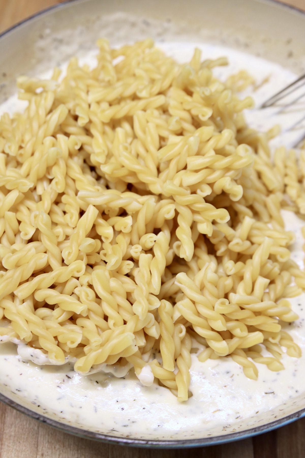 cooked gemelli pasta in a pan with creamy sauce