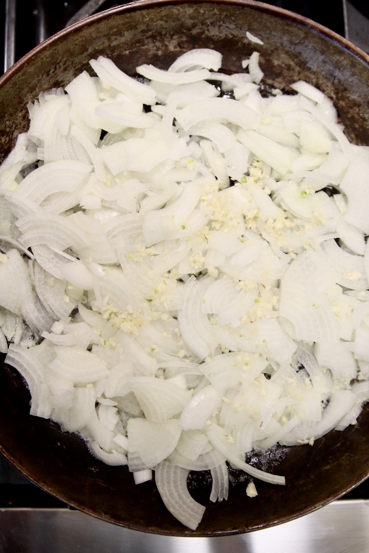 skillet with sliced onions and minced garlic 