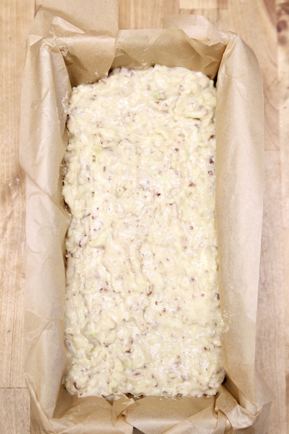 parchment lined loaf pan with apple bread batter