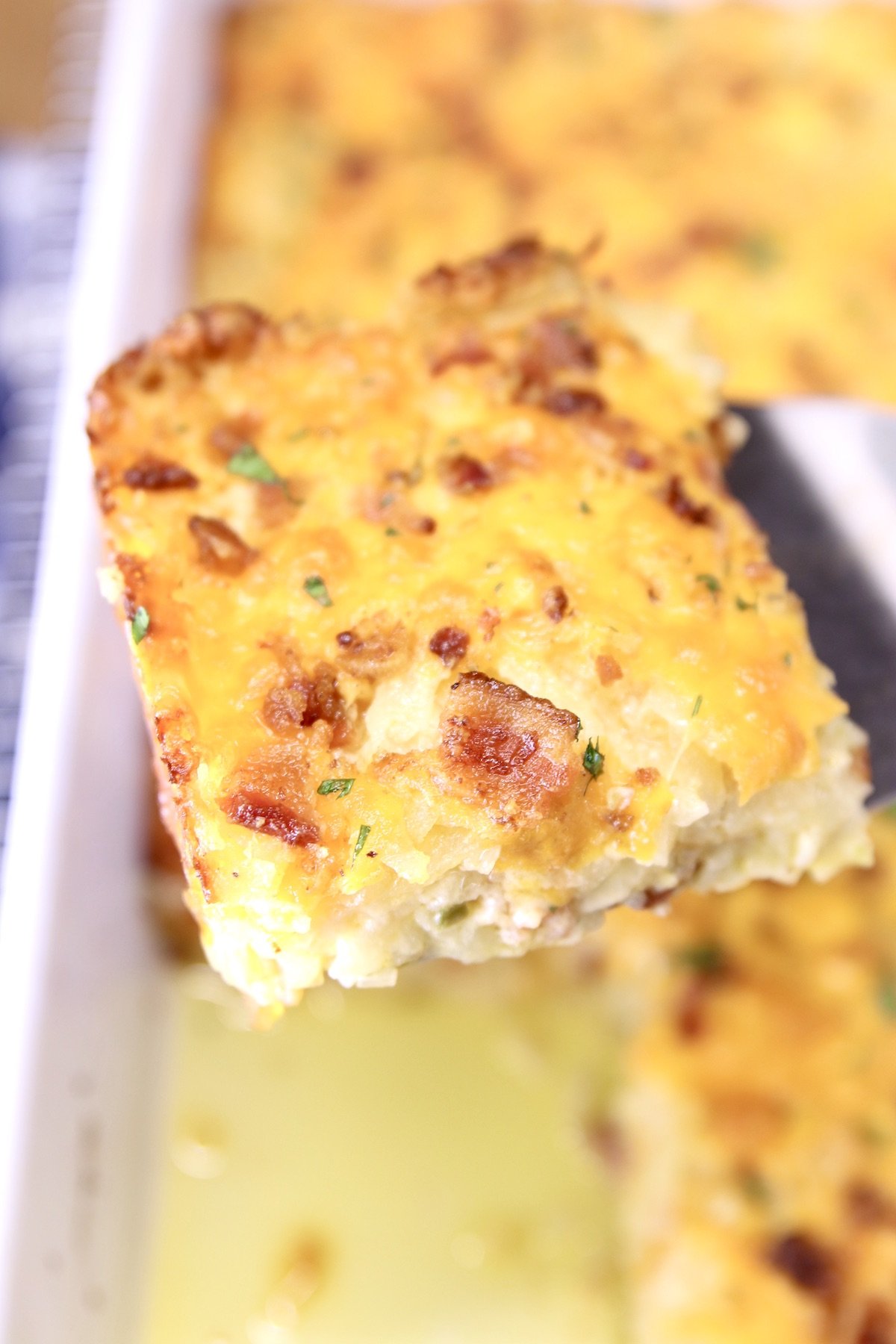 slice of hashbrown casserole on a spatula - up close