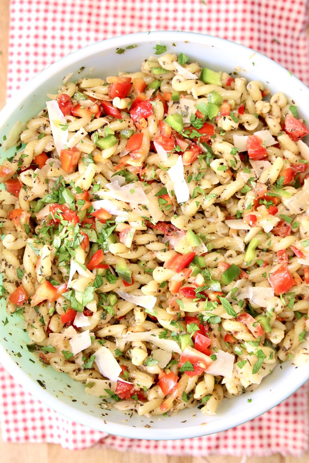 bowl of pasta salad with tomatoes, peppers, cheese on a red napkin